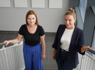 Melanie Bloch-Schönthier links im Bild mit blauer Hose und schwarzem T-Shirt. Rechts im Bild Lisa Hirschmann mit dunkler Jeans, weißem T-Shirt und dunkelblauem Blazer. Die zwei laufen eine Treppe nach oben.