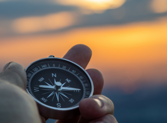 Kompass in Hand gehalten vor Sonnenuntergang
