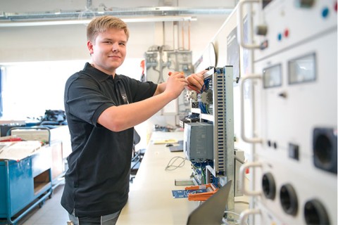 Das Bild zeigt einen jungen technischen Auszubildenden der gerade an einem Produkt arbeitet. Man sieht das technische Innenleben des Geräts.