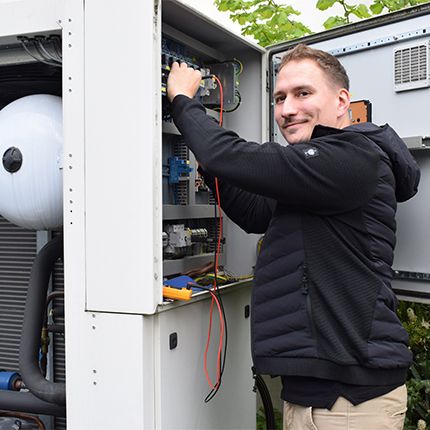 Ein Servicetechniker von Glen DImplex steht an einem Medizinkühler. Der Schaltschrank ist geöffnet und der Techniker misst etwas am Gerät. Er blickt in die Kamera und lächelt.