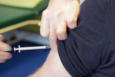 Eine Impfdosis wird mit einer Spritze in einen Oberarm verabreicht.