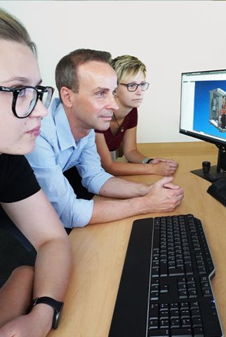 Drei Produktdesigner - ein Mann & zwei Frauen - sitzen vor zwei großen Monitoren und begutachten 3D-Modelle von Wärmepumpen.