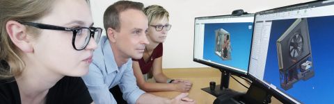 Drei Produktdesigner - ein Mann & zwei Frauen - sitzen vor zwei großen Monitoren und begutachten 3D-Modelle von Wärmepumpen.