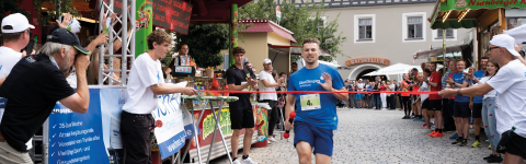 Mann in blauem Shirt läuft in Ziel ein mit Staffelstab